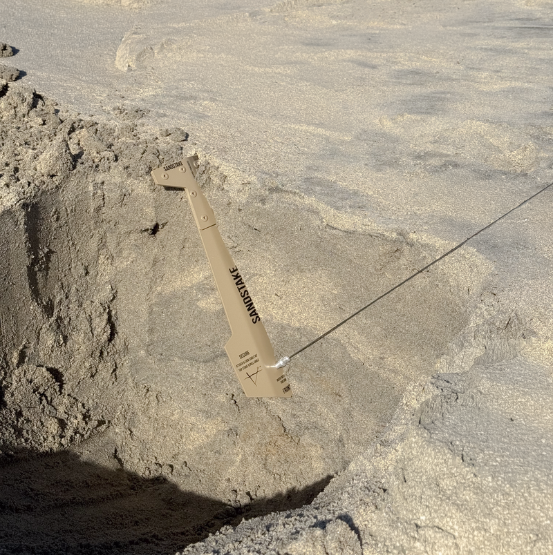 Cross-section of Sandstake buried in sand, showing the correct 90 degree angle between stake and guyline.