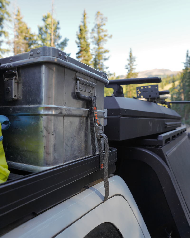 Storage box tied down with 3ft straight end Rollercam straps on a vehicle in a forest