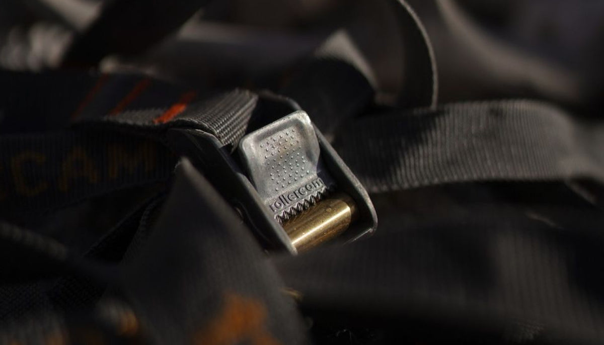 Official Rollercam Engineering photograph showing the branded thumb release, brass roller, cam body, and webbing